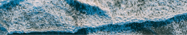 Aerial view of ocean waves crashing in parallel lines, creating white foam patterns.